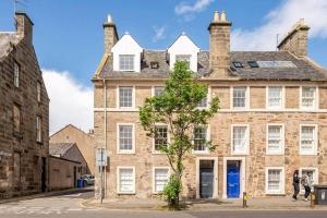 an old brick building with a tree in front of it at Skye Sands - South Street Residence - St Andrews in St. Andrews