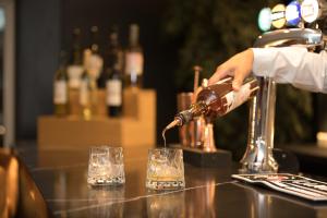 a person pouring a drink into a glass at Park Inn by Radisson Bournemouth in Bournemouth