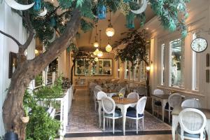 ein Restaurant mit Tischen und Stühlen und einem Baum in der Unterkunft Noor Hotel in Bandung