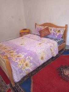 1 cama con edredón púrpura y almohadas en Gite d'étape taourirte, en Kalaat MGouna