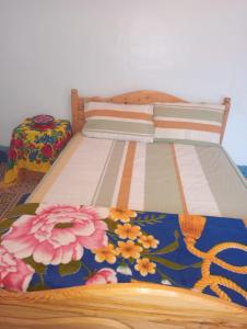 Una cama con una colcha con flores. en Gite d'étape taourirte, en Kalaat MGouna
