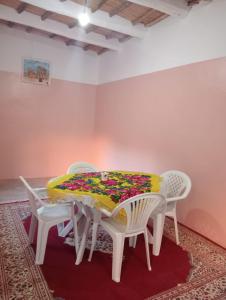 mesa de comedor con sillas blancas y mantel colorido en Gite d'étape taourirte, en Kalaat MGouna