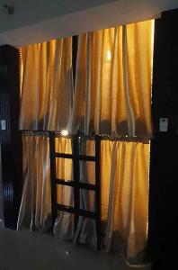 a window with a ladder in front of a curtain at C Place - Capsule A in Manila