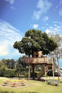 un parque infantil con una casa en un árbol en un parque en Camping de Meibeek en Ruurlo