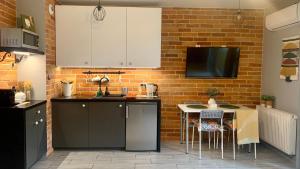 a kitchen with a table and a brick wall at Roztocka studio, free parking, 1 tram to the city & PGE National Stadion, by Cosmo Spirit in Warsaw +6 photos