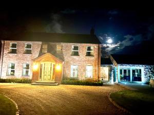 a large brick house at night with a full moon at Ballyheifer House - a beautiful 5 bedroom home. in Magherafelt