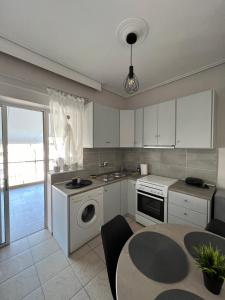 una cocina con armarios blancos y una mesa con mesa en TopCentral Apartment, en Larisa