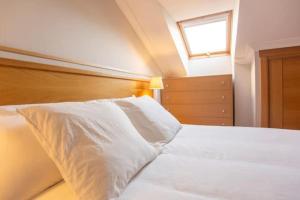 een slaapkamer met een bed met witte lakens en een raam bij Precioso ático en Sanxenxo in Sanxenxo