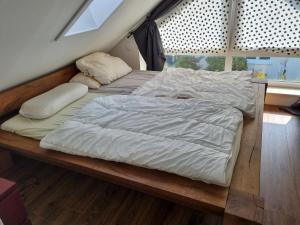 ein Bett mit weißer Bettwäsche und Kissen auf einer hölzernen Plattform in der Unterkunft Ferienhaus Bojenweg in Rostock