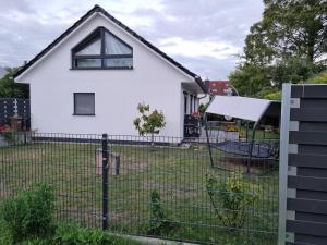a white house behind a fence at Ferienhaus Bojenweg in Rostock