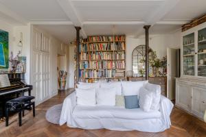 a living room with a white couch and bookshelves at Veeve - Artist's Imprint in Paris