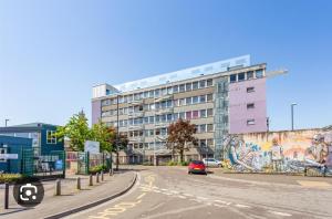 a car driving down a street with a building with a mural at Trendy, urban open plan apartment (City centre) in Bristol