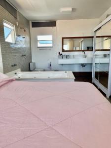 y baño con cama rosa y bañera. en Santinho Ocean View House, en Florianópolis