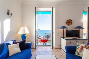 a living room with a blue couch and a television at VOLTI ON THE BAY AP4386 By Riviera Holiday Homes in Villefranche-sur-Mer