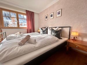 a bedroom with a large white bed with a window at Hillside One - Ski-In Ski-Out Apartments am Arlberg in Warth am Arlberg
