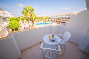 einen Balkon mit einem Tisch, Stühlen und einem Pool in der Unterkunft Blau Punta Reina in Cala Mendia