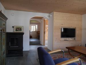 a living room with a fireplace and a tv on a wall at Casa Vanellus / Vignogn / Val Lumnezia / near Laax in Vigens