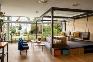 a living room with a couch and tables and windows at Vienna House Easy by Wyndham Günzburg in Günzburg
