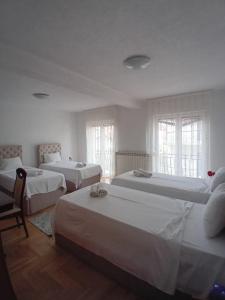 a bedroom with three beds and two windows at Hotel Montenegro in Struga