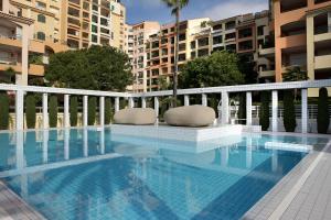 a swimming pool with two chairs sitting next to some buildings at Columbus Hotel Monte-Carlo, Curio Collection by Hilton in Monte Carlo