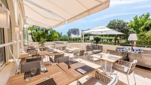 un patio al aire libre con mesas, sillas y una sombrilla en Columbus Hotel Monte-Carlo, Curio Collection by Hilton en Montecarlo