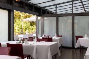 a restaurant with white tables and chairs and windows at Amedia Weiden, Trademark Collection by Wyndham in Weiden