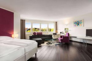 a hotel room with a bed and a living room at Amedia Weiden, Trademark Collection by Wyndham in Weiden