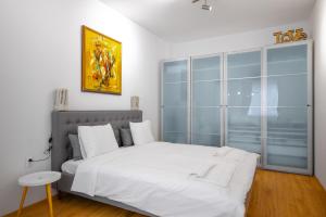 a bedroom with a white bed and a large window at Modern 2BD Flat with Prime Location and Workspace in Sofia