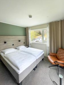 a bedroom with a bed and a chair and a window at Lærdal Hotel in Lærdalsøyri