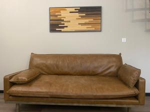 a brown leather couch sitting under a painting on a wall at Villas de La Ferme Du Gros Noyer in Malaucène