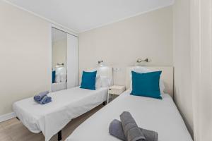- 2 lits dans une chambre blanche avec des oreillers bleus dans l'établissement Home2Book Modern Apt Puerto del Carmen, Terrace, à Puerto del Carmen