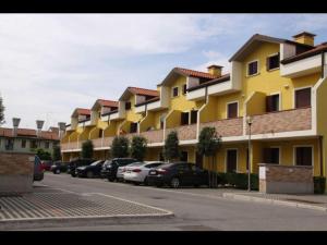 un gran edificio amarillo con coches aparcados en un aparcamiento en Adorable flat with attic in residence, en Rosapineta