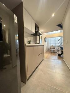 a kitchen with white cabinets and a living room at Luxury apto doble altura Bogotá in Bogotá