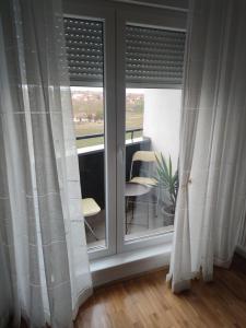 a room with windows with curtains and a table and chairs at Apartman 022 in Smederevska Palanka