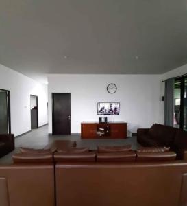 salon z kanapą i zegarem na ścianie w obiekcie Villadamailembang w mieście Padasul