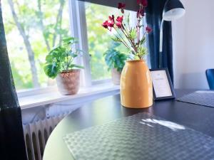 un vase orange assis sur une table avec des fleurs. dans l'établissement Strandgården Karlstad, à Karlstad