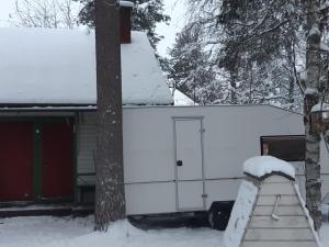 a snow covered trailer parked next to a house at Garden Caravan in Rovaniemi