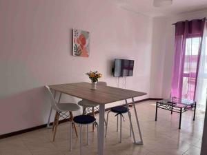 a dining room table with chairs and a vase of flowers at Cozy 2 Bedroom in Olhão in Quelfes