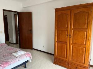 um quarto com um armário de madeira e uma cama em Cozy 2 Bedroom in Olhão em Quelfes