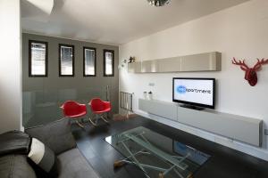 - un salon avec une télévision et des chaises rouges dans l'établissement Veoapartment Relator Terraza, à Séville