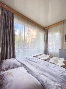 a bedroom with a large bed with a large window at уютная студия Maksim in Batumi