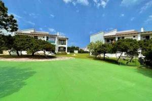 um grande campo verde em frente a um edifício em BoschApartamento de 2 dormitorios y con piscina em Ciutadella