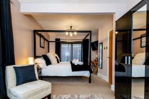 1 dormitorio con cama, silla y espejo en The Gower Hotel en Swansea