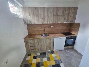 een kleine keuken met houten kasten en een wastafel bij Apartman Capital Novi Grad in Bosanski Novi