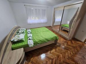 een slaapkamer met een bed met groene lakens en een spiegel bij Apartman Capital Novi Grad in Bosanski Novi