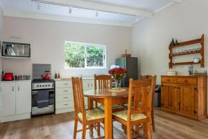 eine Küche mit einem Holztisch und Stühlen sowie eine Küche mit weißen Schränken in der Unterkunft Forest Glades in Knysna