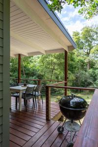 a covered deck with a grill and a table and chairs at Forest Glades in Knysna