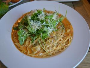 a white plate with a pizza with noodles and greens at The White Hart Country Inn in Fulbourn