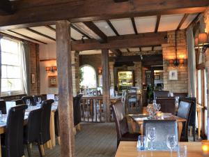 uma sala de jantar com mesas e cadeiras de madeira em The White Hart Country Inn em Fulbourn