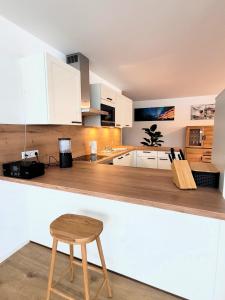 eine Küche mit weißen Schränken und einem Holzhocker in der Unterkunft Winterberg Appartement 21129 in Winterberg